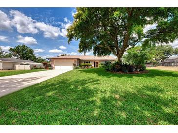 Charming single-story home with a lush green lawn, mature shade tree, and well-maintained landscaping at 6011 91St E St, Bradenton, FL 34202