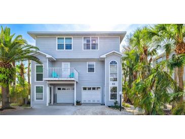 Two-story home exterior featuring light blue siding, a balcony with blue chairs, and lush tropical landscaping at 6250 Holmes Blvd # 63, Holmes Beach, FL 34217