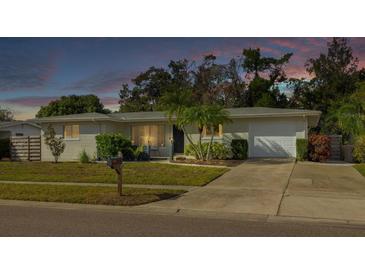 Charming single-story home with a well-manicured lawn and mature landscaping at dusk at 6442 Colonial Dr, Sarasota, FL 34231