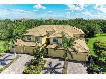 Elegant home with a red tiled roof, lush landscaping and three-car garage at 6907 Grand Estuary Trl # 104, Bradenton, FL 34212
