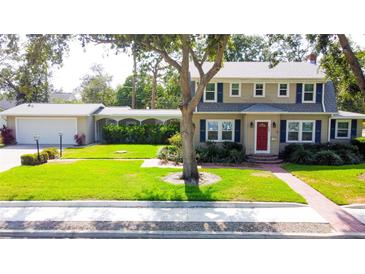 Charming two-story home featuring a red front door, lush landscaping, and a detached garage with breezeway at 708 32Nd W St, Bradenton, FL 34205