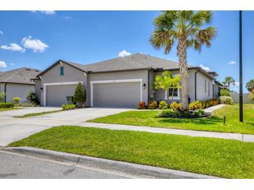 Attractive home exterior with a gray facade, a double garage, and vibrant landscaping at 8541 Whispering St, Sarasota, FL 34240
