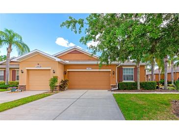 Charming single-story home with a well-manicured lawn and a two-car garage under a sunny blue sky at 11455 52Nd E Ct, Parrish, FL 34219