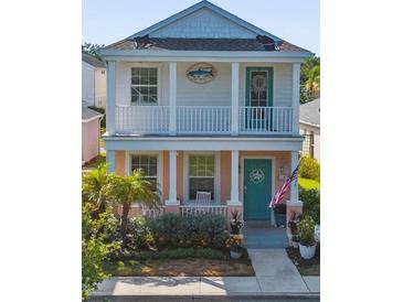 Charming two-story home with a welcoming front porch, coastal decor, and lush landscaping at 12520 Shimmering Oak Cir, Venice, FL 34293