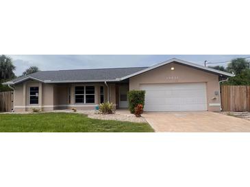 Charming single-story home featuring a well-maintained lawn, neutral paint, and a two-car garage at 14432 Mcclellan Ave, Port Charlotte, FL 33953