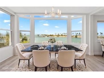 Bright dining room boasts large windows showcasing waterfront views and a modern black marble table at 174 Golden Gate Pt # 21, Sarasota, FL 34236