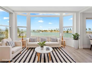Bright living room boasts a large bay window with scenic waterfront views and stylish decor at 174 Golden Gate Pt # 21, Sarasota, FL 34236