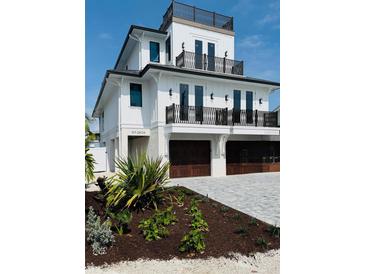 Beautiful three-story home featuring a modern design with balconies and dark wood garage doors at 2809 Avenue E, Holmes Beach, FL 34217