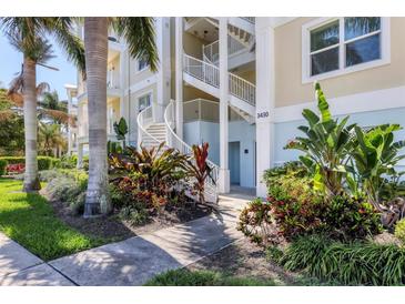Exterior view of building with lush landscaping, white railings, and a graceful spiral staircase at 3430 77Th W St # 103, Bradenton, FL 34209