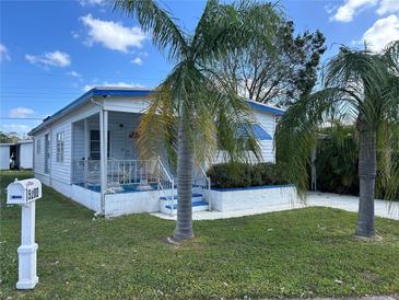 Charming single-story home with a blue and white exterior, lush landscaping and cozy front porch at 5268 Boca Raton Ave, Sarasota, FL 34234