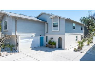 Two-story home features an attached garage, blue doors, white accents, and a well-maintained yard at 5385 Avenida Del Mare, Sarasota, FL 34242