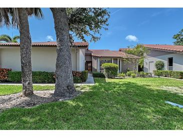 Charming single-story home with a well-maintained lawn, mature trees, and a red tile roof at 6096 Wilshire Blvd # 9, Sarasota, FL 34238