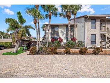 Inviting condo featuring lush landscaping, brick paved entrance and swaying palm trees on a sunny day at 6204 Midnight Pass Rd # 201, Sarasota, FL 34242