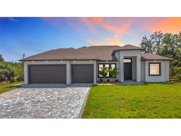 Beautiful exterior of home with a three car garage, brick driveway, and well manicured front lawn at 7152 Bougainvillea St, Englewood, FL 34224