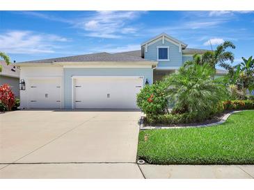 Charming two-story home with a three-car garage and lush landscaping against a brilliant blue sky at 13918 Old Creek Ct, Parrish, FL 34219