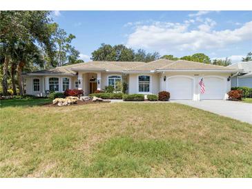 Inviting single-story home featuring a well-manicured lawn, beige exterior, and two-car garage at 2067 Tocobaga Ln, Nokomis, FL 34275