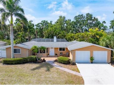 Charming ranch-style home featuring a two-car garage, lush landscaping, and inviting front porch at 2726 Silver King Way, Sarasota, FL 34231