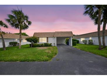 Charming villa featuring a covered carport, lush landscaping, and a well-maintained lawn at 2733 Riverbluff Pl # V57, Sarasota, FL 34231