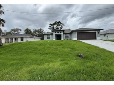 Beautifully landscaped home featuring a well-maintained lawn and modern architectural details at 2881 Pope St, North Port, FL 34287
