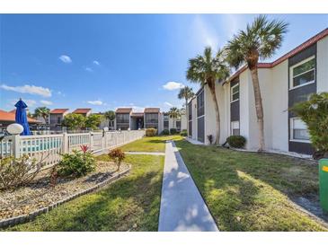 View of condos with tropical landscaping, walkway, and a glimpse of the community pool at 3269 Beneva Rd # 203, Sarasota, FL 34232