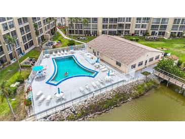 Aerial view of the community pool, showing lounge chairs, tables with umbrellas, and access to the waterfront at 3702 Lake Bayshore K-412 Dr # 412, Bradenton, FL 34205