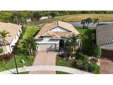 Lovely aerial view of home with clay tile roof, lake view, and beautiful landscaping in tropical community at 5987 Snowy Egret Dr, Sarasota, FL 34238