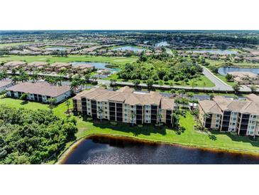 Scenic aerial view of condo building with golf course and lakes in a well-manicured community at 6519 Grand Estuary Trl # 107, Bradenton, FL 34212