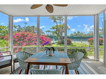 The screened lanai has a table and chairs, ceiling fan and a colorful view of the surrounding landscaping and tennis courts at 1226 Siesta Bayside Dr # 1226C, Sarasota, FL 34242