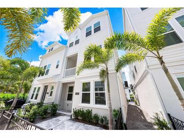 Beautiful two-story townhome with white siding, a small balcony, and lush tropical landscaping at 2408 Ezzell Ct, Sarasota, FL 34237