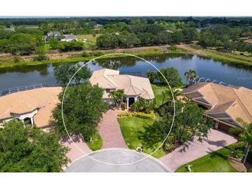 Stunning aerial view of waterfront home with brick driveway, lush landscaping, and private pool at 2496 Farms Ct, Sarasota, FL 34240