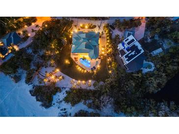Stunning aerial view showcasing a luxurious home with a backyard pool, complemented by manicured landscaping and ambient lighting at 26 Sandy Hook S Rd, Sarasota, FL 34242