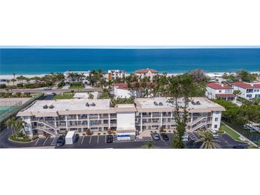 A beautiful aerial view of a beachfront apartment complex with stunning ocean views and palm trees at 3320 Gulf Of Mexico Dr # 307C, Longboat Key, FL 34228