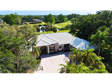 Stunning home with a paver driveway and lush landscaping, with golf course and pond views in the background at 3362 Charles Macdonald Dr, Sarasota, FL 34240