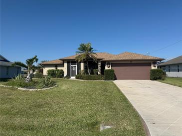 Charming single-story home with a well-maintained lawn, decorative palm trees and a two car garage at 40 Mariner Ln, Rotonda West, FL 33947