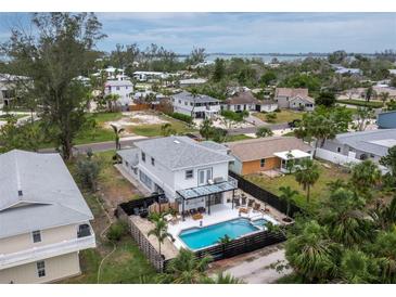 Aerial view of backyard featuring pool, patio, and fenced yard with views of surrounding neighborhood and distant bay at 580 Russell St, Longboat Key, FL 34228