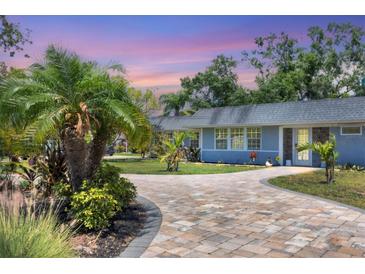 Charming home showcasing a stone driveway and meticulous landscaping with palm trees at 6931 Magellan Way, Sarasota, FL 34243