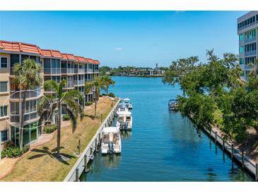Beautiful condo exterior with waterfront access, boats, and tropical landscaping at 1350 N Portofino Dr # 208, Sarasota, FL 34242