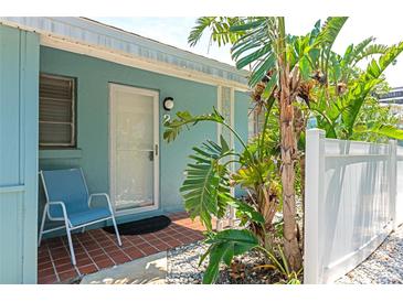 Inviting front door with red brick tile, a chair, and vibrant tropical landscaping at 170 Roosevelt Dr # 2, Sarasota, FL 34236