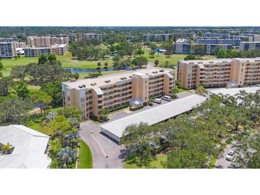 Aerial view of the condo building with golf course views, mature trees, and covered parking at 3750 Pinebrook Cir # 405, Bradenton, FL 34209