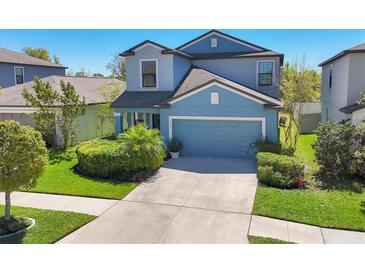 Charming two-story home featuring lush landscaping, a well-manicured lawn, and an attached two-car garage at 5033 Brickwood Rise Dr, Wimauma, FL 33598