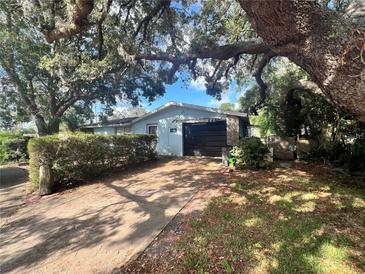 Charming single-story home featuring an attached garage and mature landscaping with a large shade tree at 5654 Oceanic Rd, Holiday, FL 34690