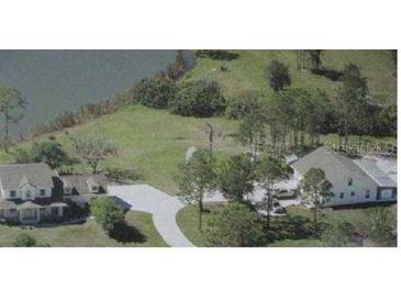 An aerial view of the home with its long driveway, and the lush yard and lake surrounding it at 60 Sinclair Dr, Sarasota, FL 34240