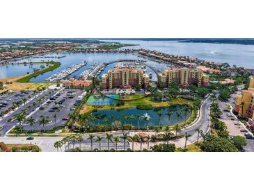 Stunning aerial view of a waterfront condo building with a marina, lake, and tennis courts at 606 Riviera Dunes Way # 306, Palmetto, FL 34221