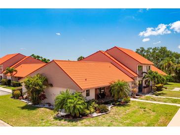 Beautiful home featuring lush landscaping, an orange roof and inviting front porch at 6462 Draw Ln # 72, Sarasota, FL 34238