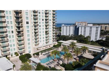 An aerial view of a luxurious pool deck surrounded by palm trees and lounge chairs at 800 N Tamiami Trl # 604, Sarasota, FL 34236