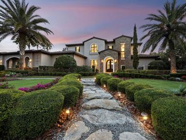 Elegant home featuring professional landscaping, a stone walkway, and lush palm trees, creating a welcoming and luxurious curb appeal at 8316 Portlight Ct, Lakewood Ranch, FL 34202