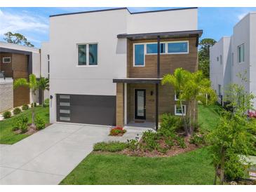 Modern two-story home boasting a sleek design, dark garage door, and beautifully landscaped front yard at 4726 Rivetta Ct, Sarasota, FL 34231