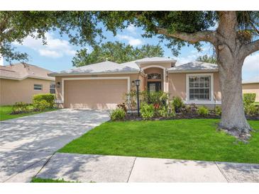 Charming single-story home featuring a manicured lawn, mature tree, and a welcoming two-car garage at 5091 Creekside Trl, Sarasota, FL 34243
