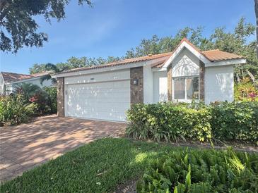 Charming home with a brick driveway, white garage door, and well-maintained landscaping at 5804 Garden Lakes Fern, Bradenton, FL 34203