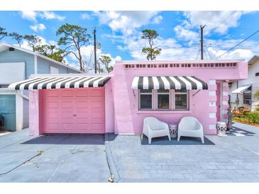Charming pink exterior with awning-covered windows and a matching garage door at 8 Desoto E St, Bradenton, FL 34208